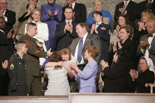 First Lady Laura Bush and Army Staff Sgt Norbert Lara, foreground left, injured in action, look on as William Norwood, whose 25-year-old son, Marine Sgt. Byron Norwood, was killed in action in Iraq, reaches out to Marine Staff Sgt. John Manuel Martinez while the dead Marine's mother, Janet Norwood, embraces Safia Taleb al-Suhail, leader of the Iraqi Womens Political Council. White House photo by Eric Draper