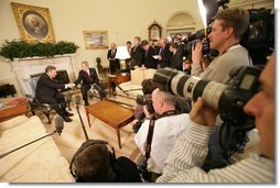 Surrounded by the members of the media, President George W. Bush greets Poland's President Aleksander Kwasniewski in the Oval Office Wednesday, Feb. 9, 2005.  White House photo by Eric Draper