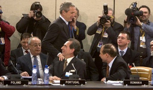 President George W. Bush walks past delegates and media as he enters a plenary session of the North Atlantic Council at NATO Headquarters in Brussels Tuesday, Feb. 22, 2005. White House photo by Eric Draper.