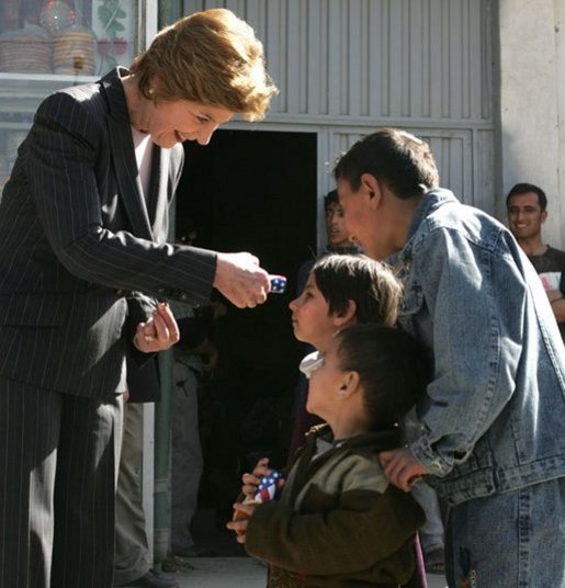 Laura Bush hands red, white and blue kaleidoscopes to youngsters outside a Kabul bakery Wednesday, March 30, 2005 during her visit to Afghanistan. White House photo by Susan Sterner