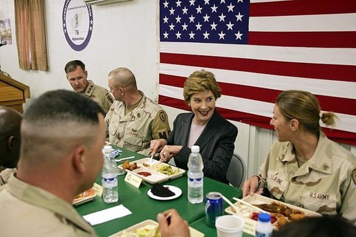 Laura Bush laughs with troops as they eat dinner in the Dragon Chow Dining Hall on Bagram Air Base in Kabul, Afghanistan Wednesday, March 30, 2005. White House photo by Susan Sterner
