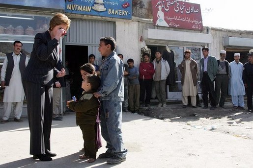 Laura Bush shows youngsters how to use a kaleidoscope outside a Kabul bakery after a stop Wednesday, March 30, 2005. The toys were gifts from the White House given by the first lady during her brief visit to Afghanistan. White House photo by Susan Sterner