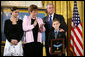 President George W. Bush places his hand on the shoulder of 11-year-old David Smith after he presented the young man with the Medal of Honor, awarded his father, Sgt. 1st Class Paul Smith, posthumously Monday during ceremonies at the White House. Joining David on stage are his step-sister Jessica and his mother, Birgit Smith.White House photo by Eric Draper
