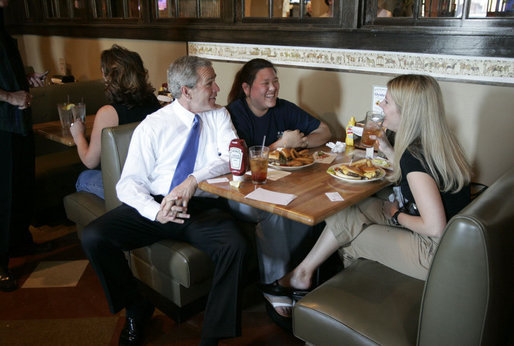 President George W. Bush takes a seat with a couple patrons at the Rockaway Athletic Club after addressing state legislators in Columbia, S.C., April 18, 2005. White House photo by Paul Morse