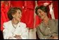 Laura Bush and former First Lady Nancy Reagan share a moment Thursday, May 12, 2005, at the John F. Kennedy Center for the Performing Arts during the unveiling of The Heart Truth’s First Ladies Red Dress Collection. White House photo by Krisanne Johnson