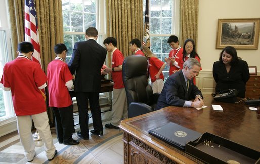 President George W. Bush signs notes to recipients of the 2005 MATHCOUNTS National Competition award during their visit to the Oval Office Thursday, May 12, 2005. White House photo by Paul Morse