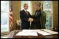 President George W. Bush and President Hamid Karzai of Afghanistan, shake hands Monday, May 23, 2005, in the Oval Office of the White House after signing a joint declaration that commits both the United States and Afghanistan to closely work together to enhance Afghanistan's long-term democracy, prosperity and security. White House photo by Eric Draper