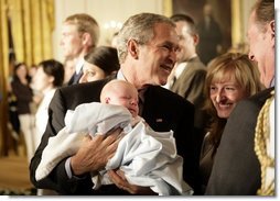 President George W. Bush holds one-month-old Trey Jones as he greets the audience Tuesday, May 24, 2005, after remarks on bioethics in the East Room of the White House.  White House photo by Eric Draper