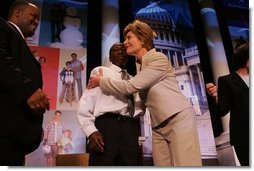 Laura Bush attends the Opening Session of the 2005 National Big Brothers Big Sisters Conference, June 9, 2005, at the Marriott Wardman Park Hotel. Washington, D.C. On-stage participants include: Vincent "Vinny" Thomas, Big Brother, left, ; and Parry Elliott, Little Brother, 13-years-old, being embraced by Mrs. Bush.  White House photo by Krisanne Johnson