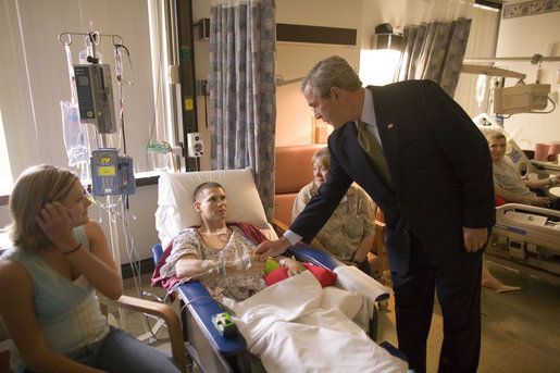President George W. Bush places a Presidential coin into the hand of Specialist Jeremy Lee as the Dallas soldier's mother, Garla Grubbs, right, and sister, Dana Lee, look on Friday, July 1, 2005. The moment came during the President's visit to the Walter Reed Army Medical Center, where Specialist Lee is recovering from wounds suffered while serving in Operation Iraqi Freedom. White House photo by Eric Draper