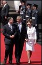 President George W. Bush and Laura Bush walk with Scotland's First Minister Jack McConnell during the playing of national anthems upon their arrival at Glasgow's Prestiwick Airport, July 6, 2005. White House photo by Paul Morse