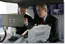 President George W. Bush talks with a Homeland Security officer, Wednesday, July 20, 2005, as President Bush is shown mobile security scanning equipment during a customs and border protection demonstration at the Port of Baltimore in Baltimore, Md.  White House photo by Eric Draper