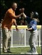 A player from the District 12 Little League Challengers of Williamsport, Pa., is given a high-five from baseball star and Tee Ball third base coach Ozzie Smith, Sunday, July 24, 2005, during a Tee Ball game on the South Lawn of the White House. White House photo by Paul Morse