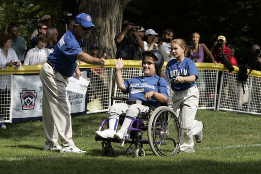 A player from the District 12 Little League Challengers from Williamsport, PA is helped to home plate by her buddy during a Tee Ball game on the South Lawn of the White House on Sunday July 24, 2005. White House photo by Paul Morse