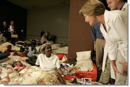 Laura Bush leans down to comfort a woman and her young child inside the Cajundome at the University of Louisiana in Lafayette, Friday, Sept. 2, 2005, during her visit to the center, one of many created to accommodate victims of Hurricane Katrina.  White House photo by Krisanne Johnson