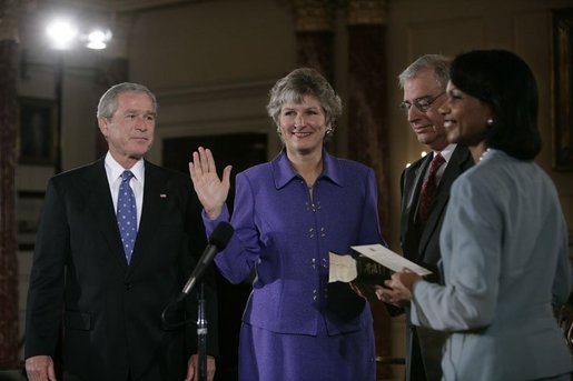 President George W. Bush watches as Karen Hughes is sworn-in by U.S. Secretary of State Condoleezza Rice, Friday, Sept. 9, 2005 at the State Department in Washington, to be the Under Secretary of State for Public Diplomacy. Jerry Hughes, Secretary Hughes' husband, holds the Bible during the ceremony. White House photo by Eric Draper