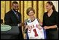 Golden State Warrior Baron Davis, left, and Phoenix Mercury guard Diana Taurasi, right, present Laura Bush with a basketball jersey at the National Book Festival Author's breakfast in the East Room Saturday, Sept. 24, 2005. White House photo by Krisanne Johnson
