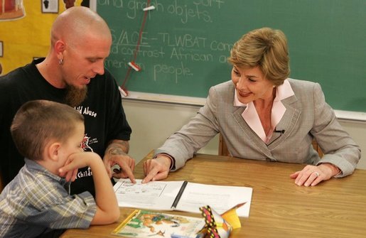 Laura Bush works with a child and father, while participating in the R.E.A.D. to Kids Training Program at J.S. Chick Elementary School in Kansas City, Mo., Tuesday, October 11, 2005. White House photo by Krisanne Johnson