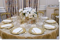The table settings in the State Dining Room for the White House dinner Wednesday, Nov. 2, 2005, in honor of the Prince of Wales and Duchess of Cornwall. Chosen by Mrs. Laura Bush, the centerpieces are sprays of white phaeleanopsis orchids displayed in vermeil vases and compliment the Clinton China and vermeil flatware.  White House photo by Shealah Craighead