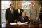 President George W. Bush is backed by U.S. Rep. Tom Latham, R-Iowa, left, U.S. Rep. Henry Bonilla, R-Texas, center, and U.S. Sen. Robert Bennett, R-Utah, Thursday, Nov. 10, 2005 in the Oval Office, as he signs H.R. 2744-Agriculture, Rural Development, Food and Drug Administration, and Related Agencies Appropriations Act, 2006. White House photo by Eric Draper