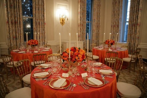 This is a view of the table settings in the State Dining Room, for the Thursday, Nov. 10, 2005 White House dinner, celebrating the National Endowment for the Arts and National Endowment for the Humanities 40th Anniversary. Chosen by Mrs. Laura Bush, the centerpieces are autumnal roses displayed in vermeil vases to compliment the Reagan China. White House photo by Paul Morse