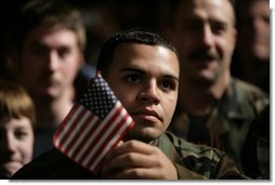 An unidentified member of the U.S. Armed Forces holds an American flag as he listens to the President’s remarks on the War on Terror, Monday Nov. 14, 2005, at Anchorage’s Elmendorf Air Force Base. The stop marked the first on a seven-day trip to Asia by the President and Mrs. Bush.  White House photo by Eric Draper