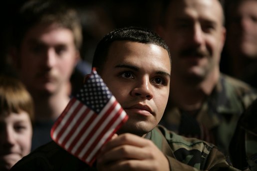 An unidentified member of the U.S. Armed Forces holds an American flag as he listens to the President’s remarks on the War on Terror, Monday Nov. 14, 2005, at Anchorage’s Elmendorf Air Force Base. The stop marked the first on a seven-day trip to Asia by the President and Mrs. Bush. White House photo by Eric Draper
