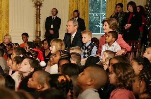 President George W. Bush and Laura Bush sit with children, Monday, Dec. 5, 2005 at the White House, as they watch a dance performance during the White House Children's Holiday Reception in the East Room. White House photo by Kimberlee Hewitt