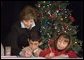 Laura Bush writes a note on a child's letter to his parent who is serving overseas, as she visits with children at the Naval and Marine Corps Reserve Center in Gulfport, Miss., Monday, Dec. 12, 2005, showing them a White House holiday video, 'A Very Beazley Christmas' featuring the Bush's dogs, Barney and Miss Beazley. White House photo by Shealah Craighead