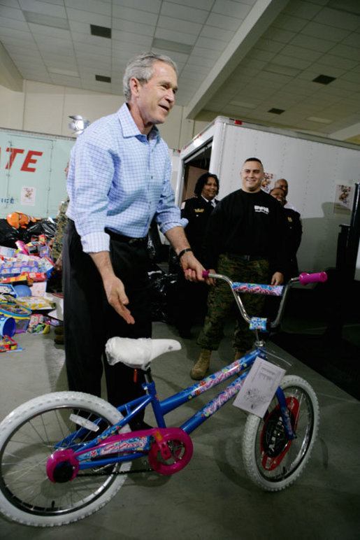 President George W. Bush helps guide a donated bicycle to a toy distribition vehicle, Monday, Dec. 19, 2005, at the "Toys for Tots" collection center at the Naval District Washington Anacostia Annex in Washington, D.C. White House photo by Kimberlee Hewitt