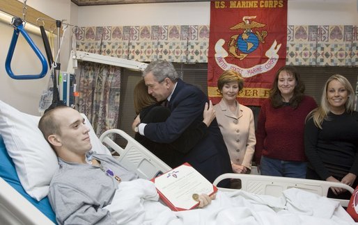 As Laura Bush looks on, President George W. Bush hugs Candy Pierson of Auburndale, Fla., after her son, Marine Cpl Jordan S. Pierson, was presented the Purple Heart for injuries suffered while serving in Iraq. The ceremony took place Wednesday, Dec. 21, 2005, at the National Naval Medical Center in Bethesda, Md. Also in the room are Cpl. Pierson's fiancée, Kirstin Martin, right, and cousin Tiffany Pierson. White House photo by Paul Morse