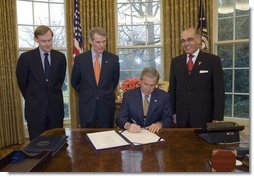 President George W. Bush signs the U.S.-Bahrain Free Trade Agreement in the Oval Office Wednesday, Jan. 11, 2006. Standing with the President are, from left: Deputy Secretary of State Robert Zoellick, U.S. Trade Representative Rob Portman, and Bahrain Ambassador Naser M. Al Belooshi.  White House photo by Paul Morse
