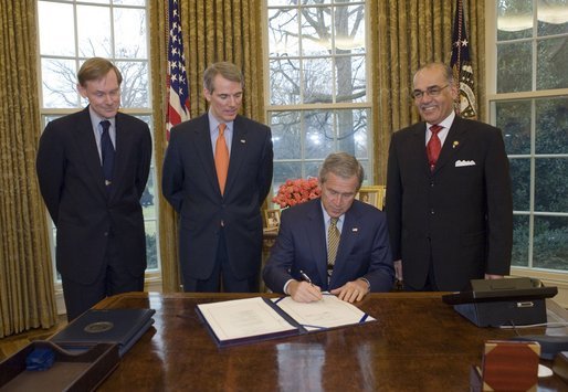 President George W. Bush signs the U.S.-Bahrain Free Trade Agreement in the Oval Office Wednesday, Jan. 11, 2006. Standing with the President are, from left: Deputy Secretary of State Robert Zoellick, U.S. Trade Representative Rob Portman, and Bahrain Ambassador Naser M. Al Belooshi. White House photo by Paul Morse