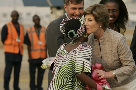 Mrs. Laura Bush embraces 11-year-old Jamila Ahmed after she presented flowers to Mrs. Bush, Tuesday, Jan. 17, 2006, upon her arrival to Abuja, Nigeria. Deputy Chief of U.S. Mission Thomas Fuery and Nigeria's Minister of Education Chinwe Obaji, are seen in the background. White House photo by Shealah Craighead