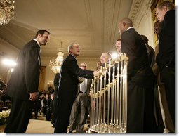 President George W. Bush welcomes Chicago White Sox players to the White House, Monday, Feb. 13, 2006 during an East Room ceremony to honor the 2005 World Series Champions. The World Series Trophy is seen foreground.  White House photo by Eric Draper