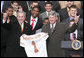 President George W. Bush holds up a University of Texas Longhorns jersey with head football coach Mack Brown, as they give the 'Hook Em Horns' sign, Tuesday, Feb. 14, 2006 on the South Lawn of the White House, during ceremonies to honor the 2005 NCAA Football Champions. White House photo by Paul Morse