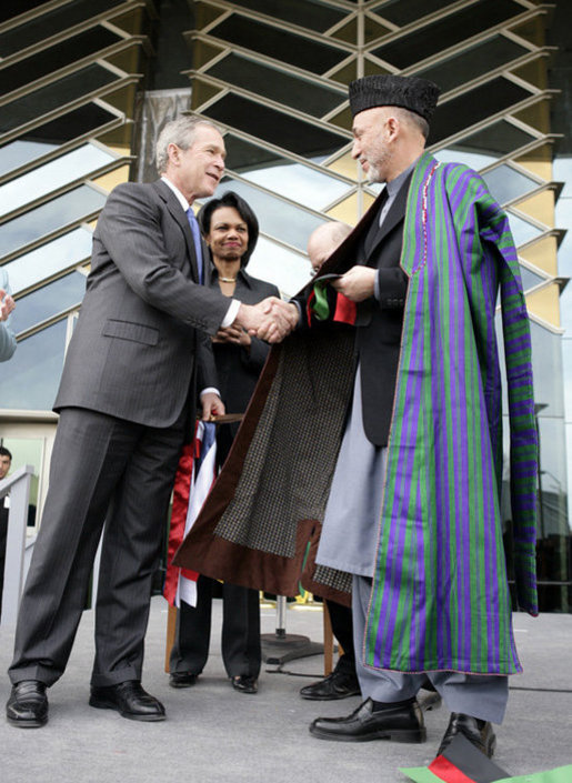 President George W. Bush and Afghanistan President Hamid Karzai shake hands after cutting the ceremonial ribbon, Wednesday, March 1, 2006, to dedicate the new U.S. Embassy Building in Kabul, Afghanistan. President Karzai thanked President Bush and the American people for their continued support to the Afghan people. White House photo by Eric Draper