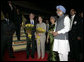 President George W. Bush and Mrs. Bush stand with flowers presented upon their arrival Wednesday, March 1, 2006, at New Delhi's Indira Gandhi International Airport where they were greeted by India's Prime Minister Manmohan Singh, right, and his wife, Gursharan Kaur. White House photo by Eric Draper