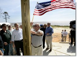 President George W. Bush watches as homeowner Jerry Akins places a flag outside his home Wednesday, March 8, 2006 in Gautier, Miss., on the site where the Akins family is rebuilding their home destroyed by Hurricane Katrina. White House photo by Eric Draper
