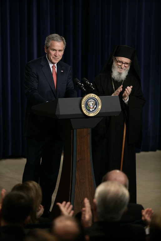 President George W. Bush is applauded by Archbishop Demetrios from the Greek Orthodox Church of America, Friday, March 24, 2006 at the Eisenhower Executive Office Building in Washington, where President Bush addressed an audience celebrating Greek Independence Day and honored the 185th anniversary of Greece's Independence. White House photo by Eric Draper