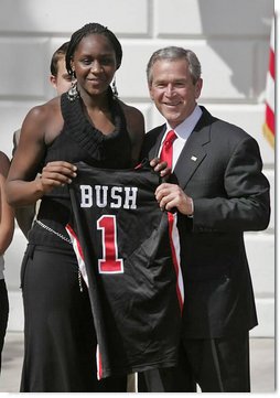President George W. Bush stands with Crystal Langhorne, captain of the University of Maryland Women's Basketball Team, during a South Lawn ceremony honoring the 2005 and 2006 NCAA champions Thursday, April 6, 2006. The University of Maryland also won national titles in women's field hockey and men's soccer.  White House photo by Paul Morse
