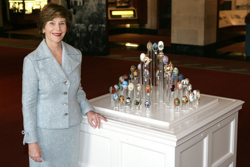 Mrs. Laura Bush poses for a photo next to the State Egg Display which exhibits a decorated egg from a select artist of each state Thursday, April 6, 2006, at the White House Visitor Center. This tradition has been going on since 1994, and each year the artists vote amongst themselves to select the artist to create the following year’s commemorative egg which is presented to the President and First Lady. White House photo by Shealah Craighead