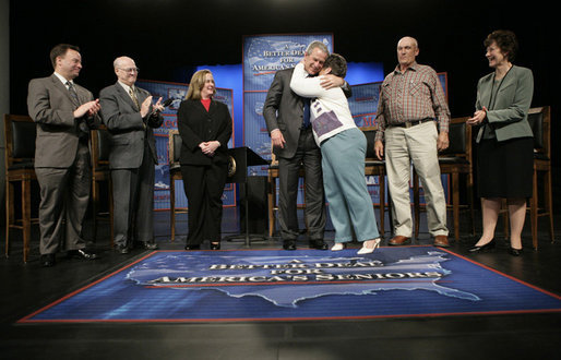 President George W. Bush is embraced by panel member Helen Robinette after concluding a conversation about Medicare prescription drug benefits at the Etta & Joseph Miller Performing Arts Center in Jefferson City, Mo., Tuesday, April 11, 2006. The President and Medicare and Medicaid Services administrator Mark McClellan, far left, met with several Missourians. They are, from left, Gerald Sooter, Jodie Baker, Helen Robinette, Bob Vanderfeltz and Linda Detring. White House photo by Eric Draper