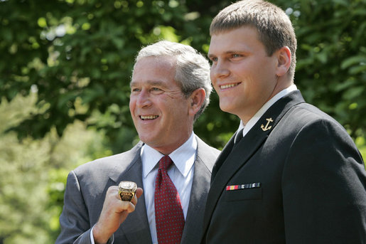 President George W. Bush sports an oversized championship ring as the stands with Midshipman Jeremy Chase of the United States Naval Academy football team during the presentation of the Commander-in-Chief Trophy to in the Rose Lawn April 25, 2006. White House photo by Paul Morse