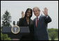 President George W. Bush and Kim Oliver, the 2006 National Teacher of the Year, wave from the podium on the South Lawn Wednesday, April 26, 2006, during a ceremony honoring the Silver Spring, Maryland kindergarten teacher. White House photo by Paul Morse