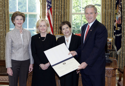 President George W. Bush and Mrs. Bush present the Preserve America award for heritage tourism to Dr. Bonnie McEwan, Executive Director, Mission San Luis of Tallahassee, Fla., left, and Mrs. Columba Bush, the First Lady of Florida, in the Oval Office Monday, May 1, 2006. White House photo by Eric Draper