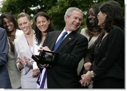 President George W. Bush laughs with members of the Sacramento Monarchs as he tries on their 2005 Women's National Basketball Association Championship ring during a congratulatory ceremony held in the East Garden at the White House Tuesday, May 16, 2006.  White House photo by Eric Draper