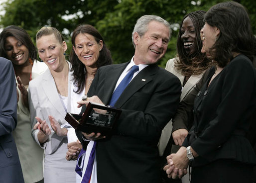 President George W. Bush laughs with members of the Sacramento Monarchs as he tries on their 2005 Women's National Basketball Association Championship ring during a congratulatory ceremony held in the East Garden at the White House Tuesday, May 16, 2006. White House photo by Eric Draper