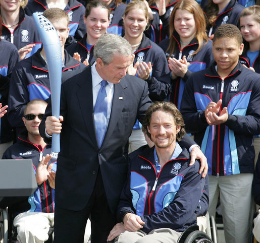 President George W. Bush is given an Olympic torch by Chris Devlin-Young, a U.S. Paralympic gold-medalist, during a South Lawn ceremony Wednesday, May 17, 2006, at the White House in honor of the 2006 U.S. Winter Olympics and Paralympics teams. White House photo by Shealah Craighead