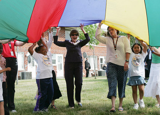 Mrs. Laura Bush participates in playing with a colorful parachute with children and staff outside the Meadowbrook Collaborative Community Center, Tuesday, June 6, 2006 in St. Louis Park. Minn. White House photo by Shealah Craighead